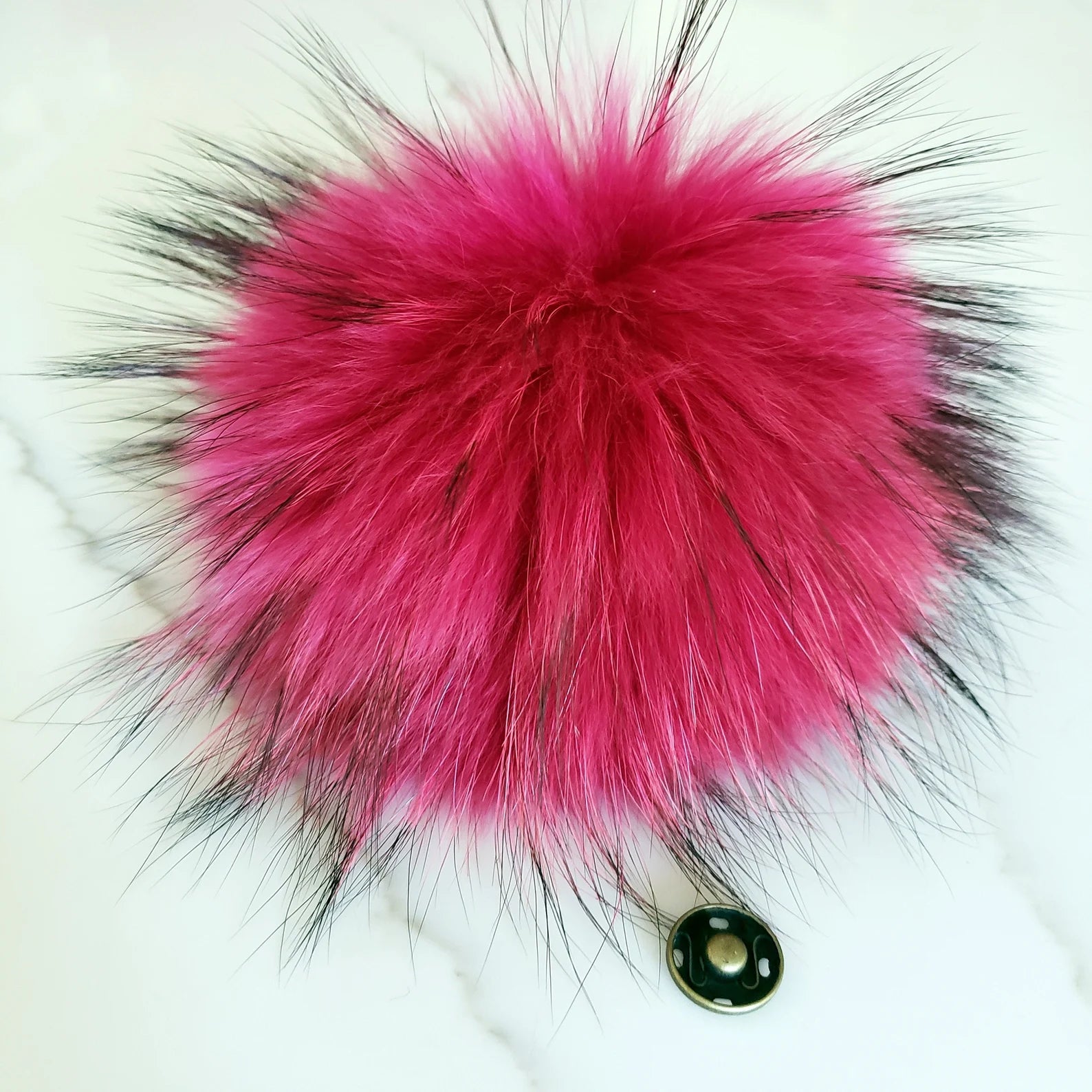 Pink and black fluffy keychain on a white background